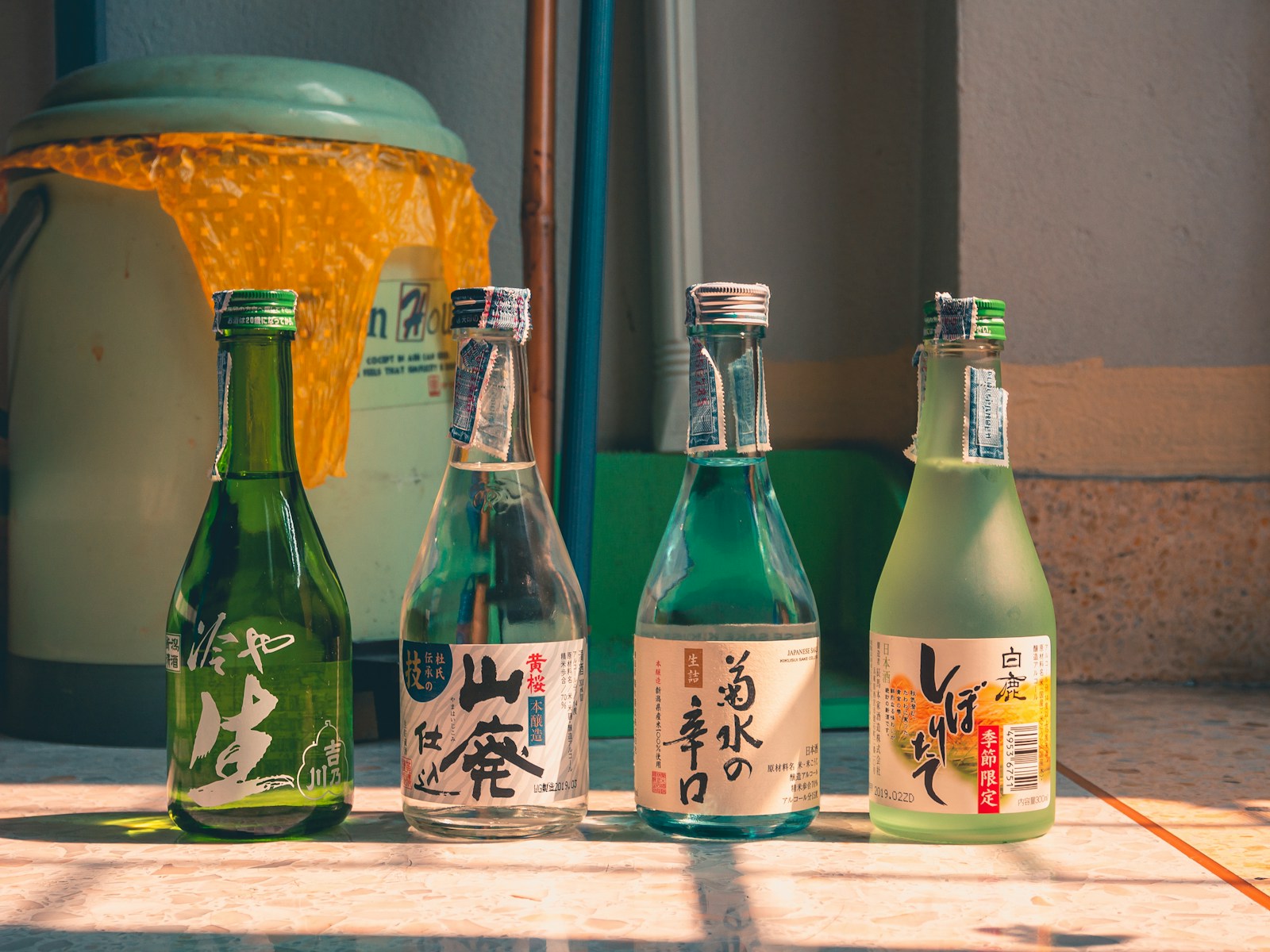 窓辺に並ぶ日本酒の小瓶4本。山廃・菊水・しぼりたてなど銘柄の異なる清酒