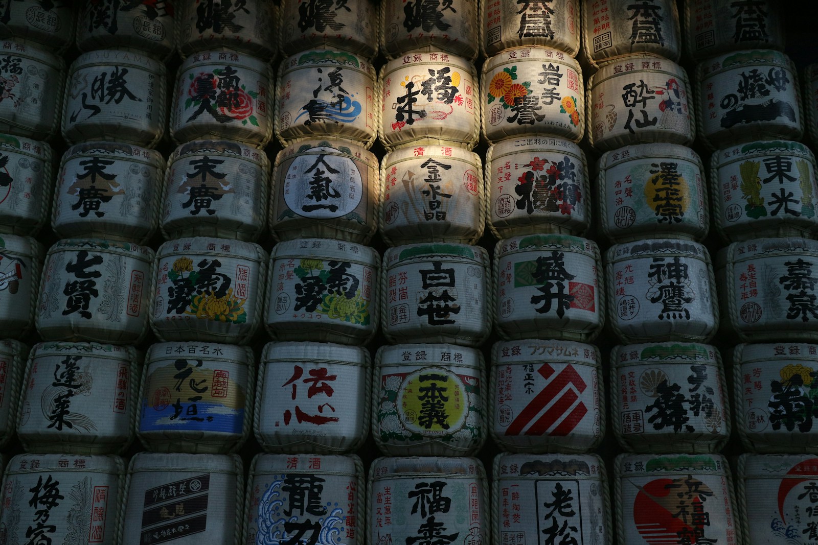 日本酒の樽が積み上げられた風景。福、勝、岩手など各蔵元の銘柄ラベルが並ぶ